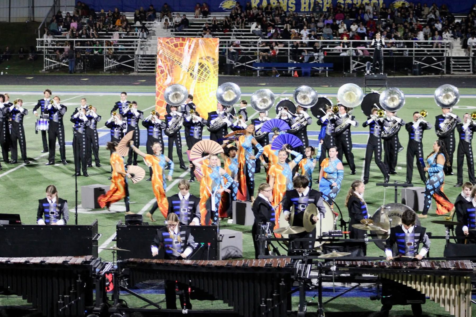 The Marching Admirals performing their halftime show, brass line behind the color guard and front ensemble